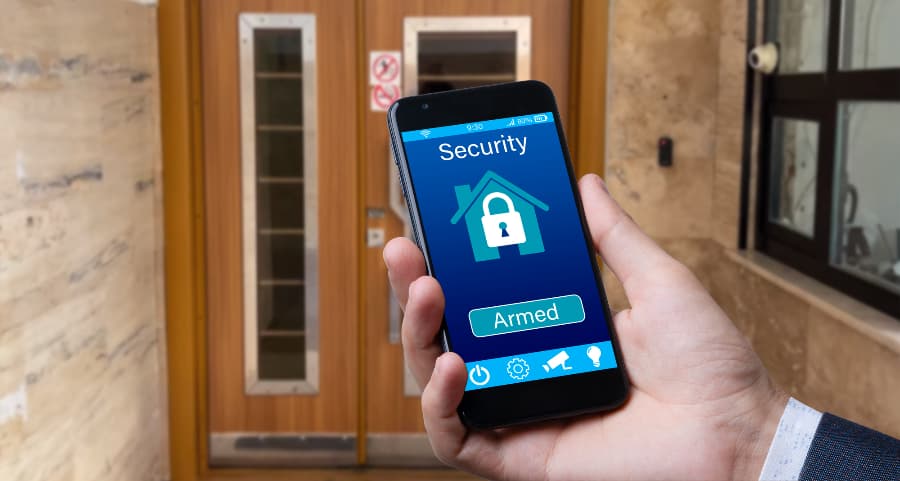 Individual using cell phone to arm a home security system